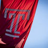 The Temple T cherry red flag waving on Main Campus on a bright sunny day