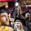 Three students wearing caps and gowns celebrating at Commencement